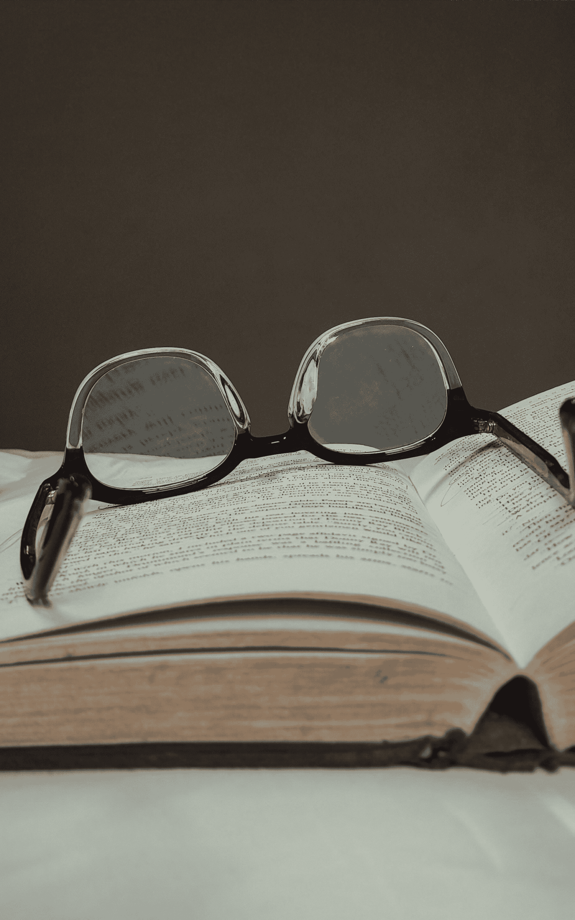 A pair of glasses and a book on a table, symbolizing academic writing and nonfiction book publishing.