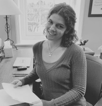 Line editor with short brown hair wearing a sweater at a desk